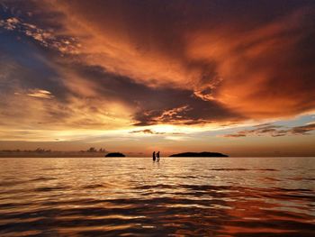 Silhouette people at beach against sky during sunset