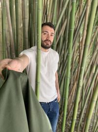 Portrait of man standing amidst bamboo plants