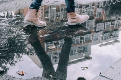 Low section of person with reflection in puddle