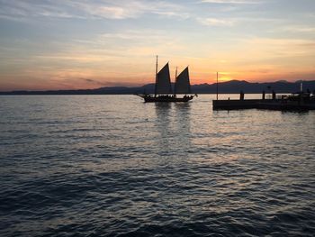 Silhouette sailboats in sea against sky during sunset