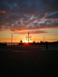 Silhouette factory against sky during sunset