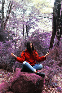 Young woman sitting on pink tree