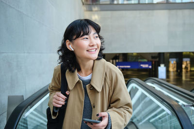 Portrait of young woman standing in city