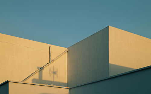 Low angle view of white building against clear blue sky during sunrise