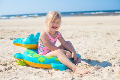 Portrait of young woman sitting on sand at beach