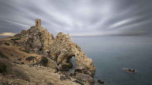 Rock formation on beach against sky