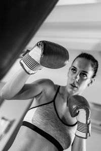 Woman hitting punching bag in boxing rink