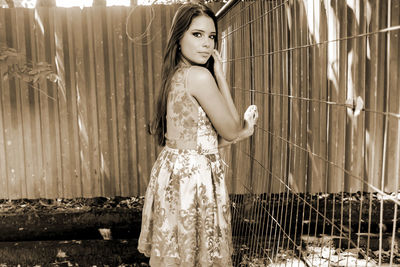 Portrait of woman standing by fence