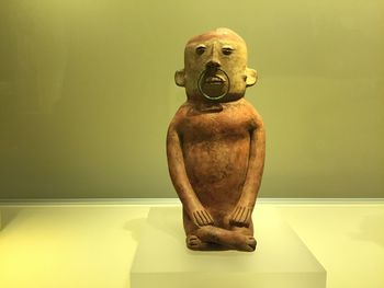 Close-up of statue on table against wall