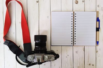 Directly above shot of camera and diary on wooden table