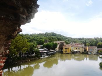 Houses by lake and buildings against sky