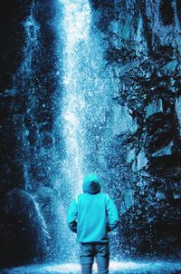 Rear view of man standing against waterfall