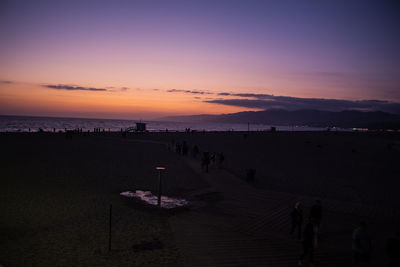 Silhouette people on beach against sky during sunset