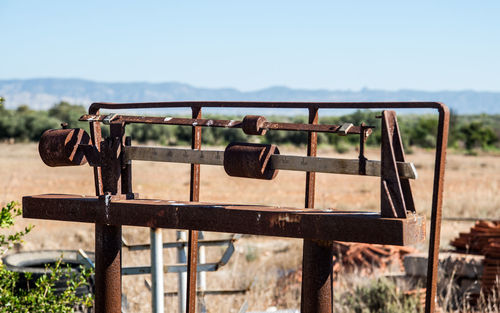 Close-up of rusty metal fence on field against sky