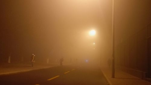 Illuminated road against sky at night