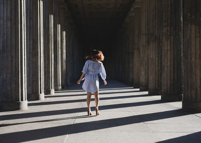 Rear view of woman standing at colonnade