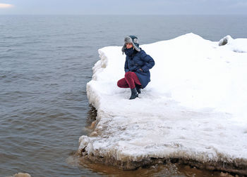 Woman standing on the snowy shore of the baltic sea.