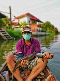 Portrait of young woman holding fish in lake