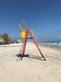 Lifeguard hut on beach against clear blue sky