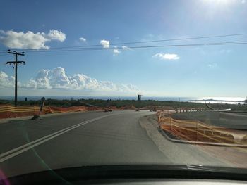 Cars on road against cloudy sky