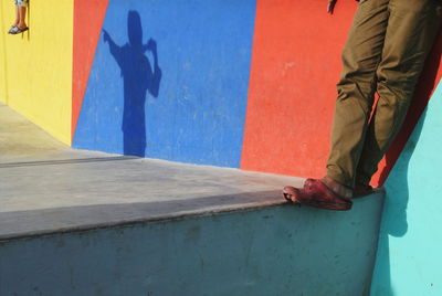 Low section of man standing on multi colored umbrella