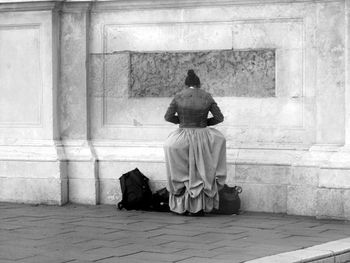 Rear view of woman sitting on staircase against building