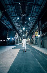 Rear view full length of woman standing at illuminated covered street market