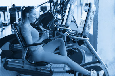 Low section of woman sitting on wheelchair in gym