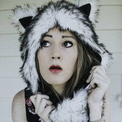 Portrait of beautiful young woman standing against white wall