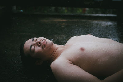 Portrait of young man lying on wet floor