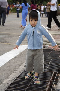 Portrait of cute boy wearing hooded shirt while standing on sewage