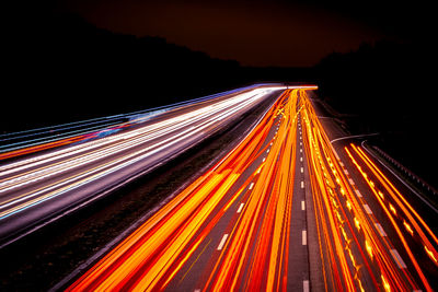 Light trails on road against sky at night