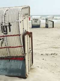 Close-up of hooded beach chairs on sand