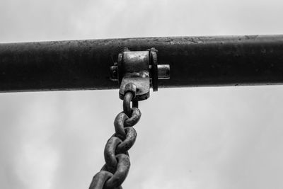 Close-up of rusty metal chain against sky