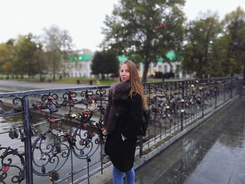 Portrait of smiling woman wearing warm clothing while standing on bridge over canal