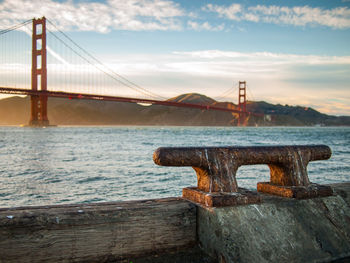 Golden gate bridge over sea against cloudy sky