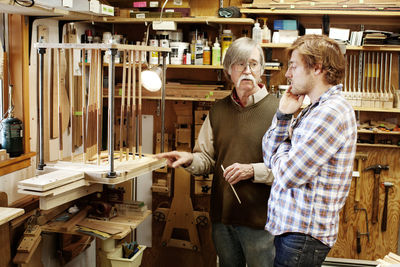 Men discussing while standing at guitar workshop