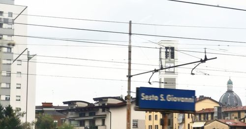 Low angle view of electricity pylon against buildings in city