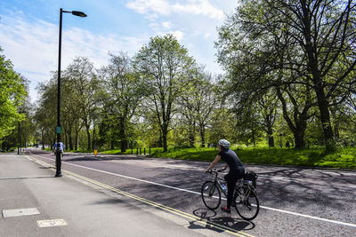 Woman riding bicycle on street against sky