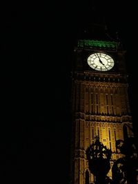 Low angle view of clock tower at night