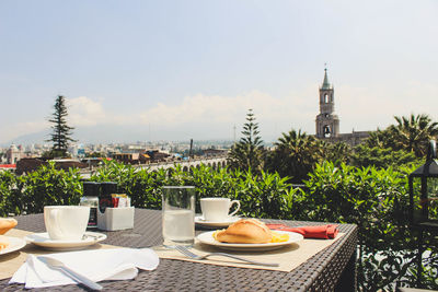 Lounge chairs and tables in city against sky