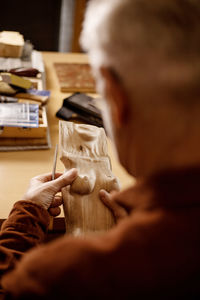 Artist is grinding wooden sculpture. carpenter working with wood in workshop. man and his hobby. 