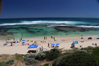 High angle view of people at beach against clear blue sky