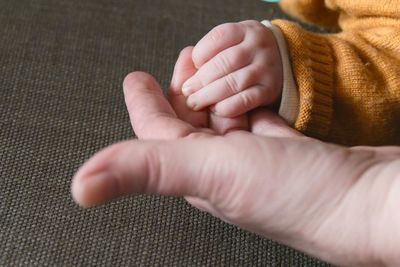 Cropped hands of parent and baby at home