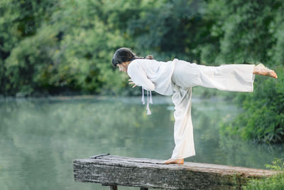 Yoga by the lake. young woman practicing warrior 3 pose or virabhadrasana iii