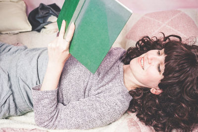 Woman reading book on bed at home