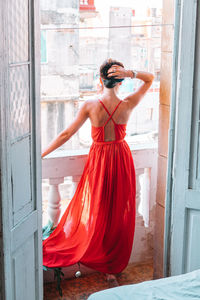 Rear view of woman standing by window