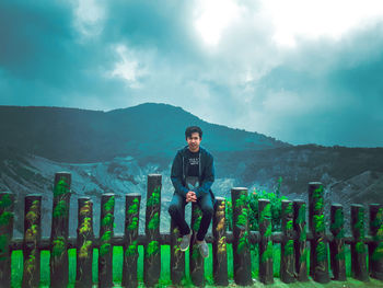 Portrait of young man standing on mountain against sky