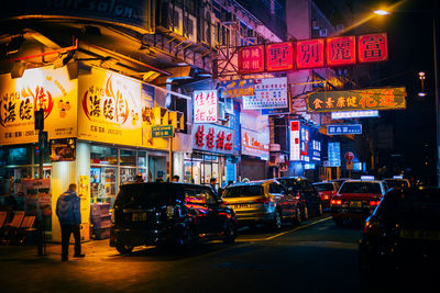 Cars on illuminated city street at night