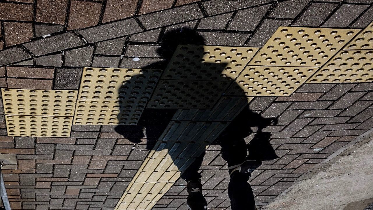 SHADOW OF MAN STANDING ON COBBLESTONE STREET